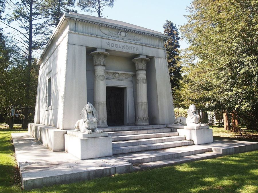An Egyptian Revival mausoleum flanked by sphinx statues among trees at Woodlawn Cemetery in the Bronx