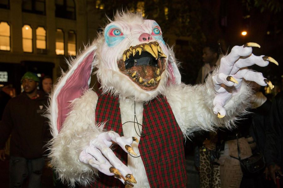A reveler in a white rabbit-monster costume with fangs and long claws on Halloween night at Union Square