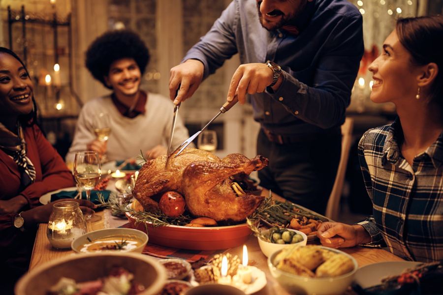 Carving a roast turkey at a candlelit Thanksgiving table at home