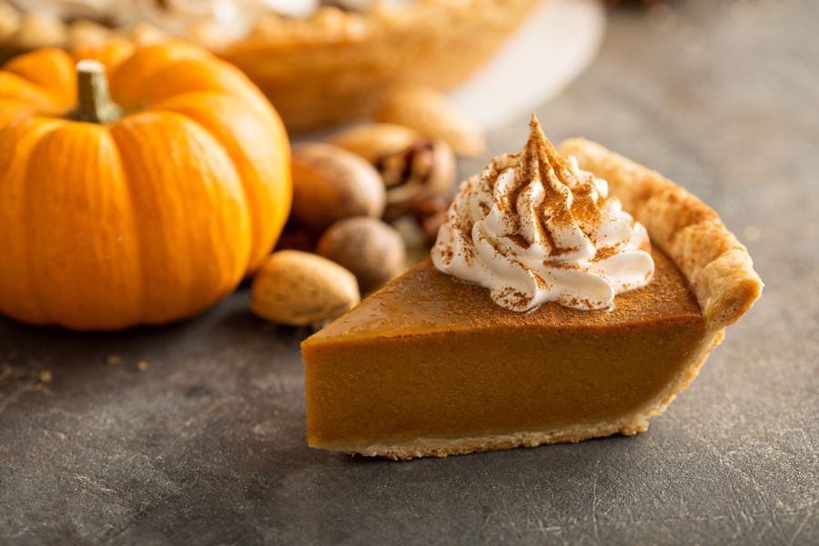 A slice of pumpkin pie topped with whipped cream and cinnamon