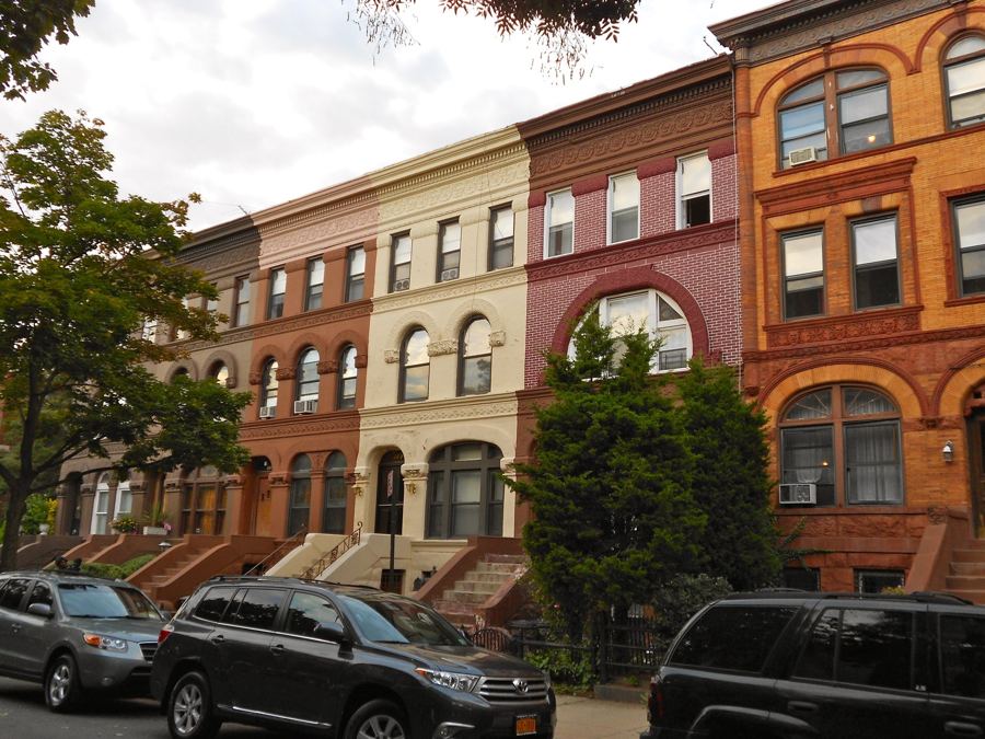 A row of brick and brownstone Romanesque Revival row houses with arched windows on Decatur Street in Bedford-Stuyvesant's Stuyvesant Heights.