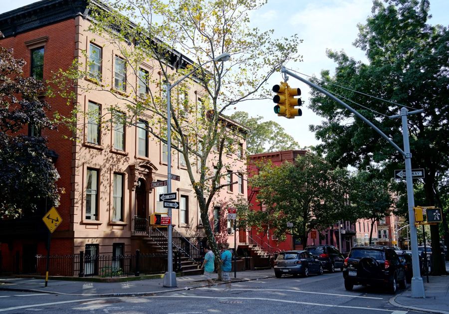 Brick and brownstone row houses at the corner of Henry and Congress Streets under leafy trees in Cobble Hill, Brooklyn.