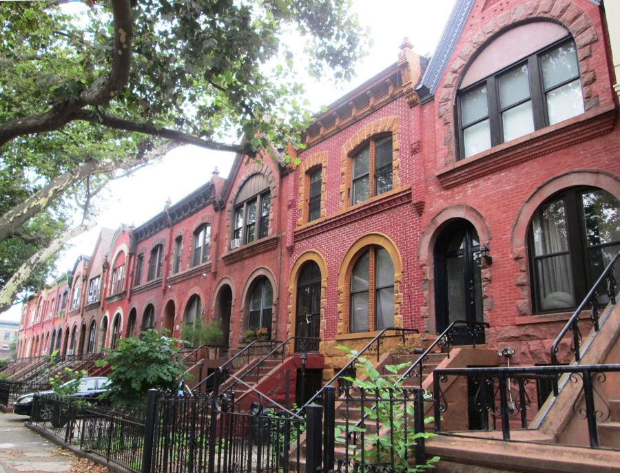 A row of red-brick Romanesque Revival row houses with arched doorways and stoops on Park Place in Crown Heights.