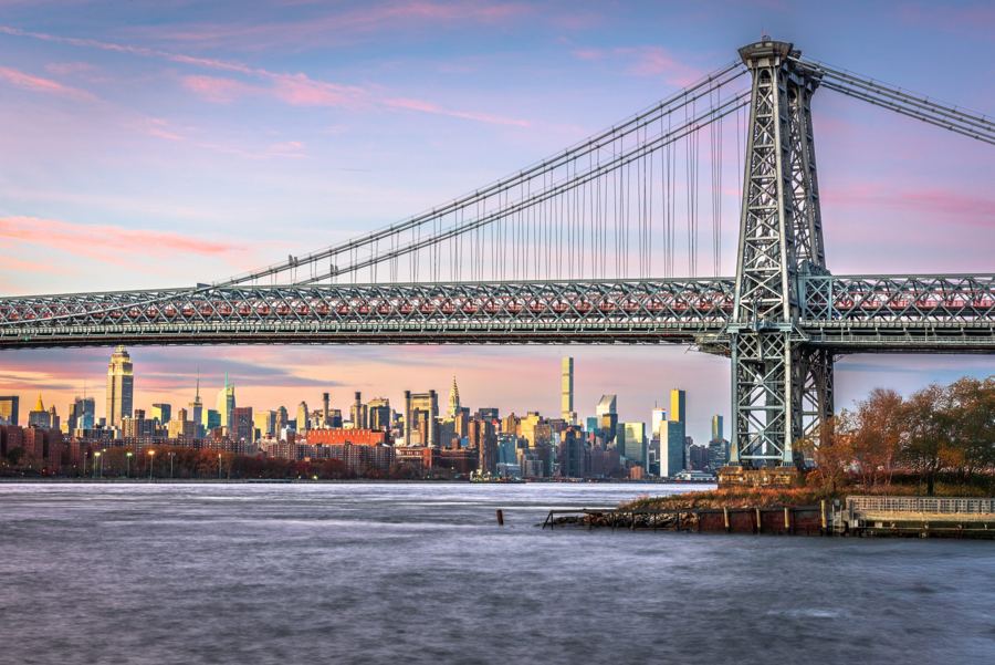 The Williamsburg Bridge at dusk with the Manhattan skyline across the East River