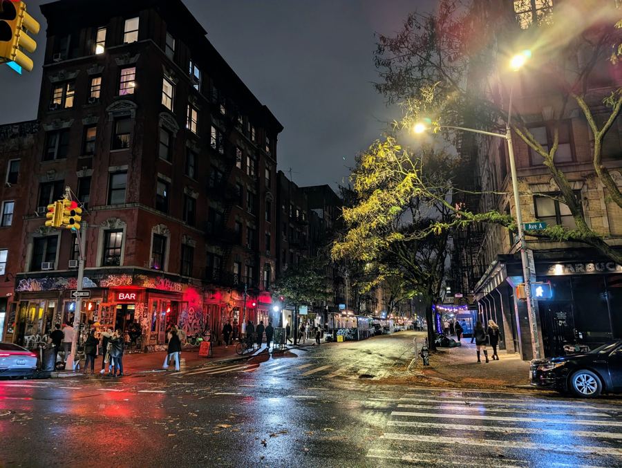 St. Marks Place at night, rain-slick pavement reflecting lit storefronts