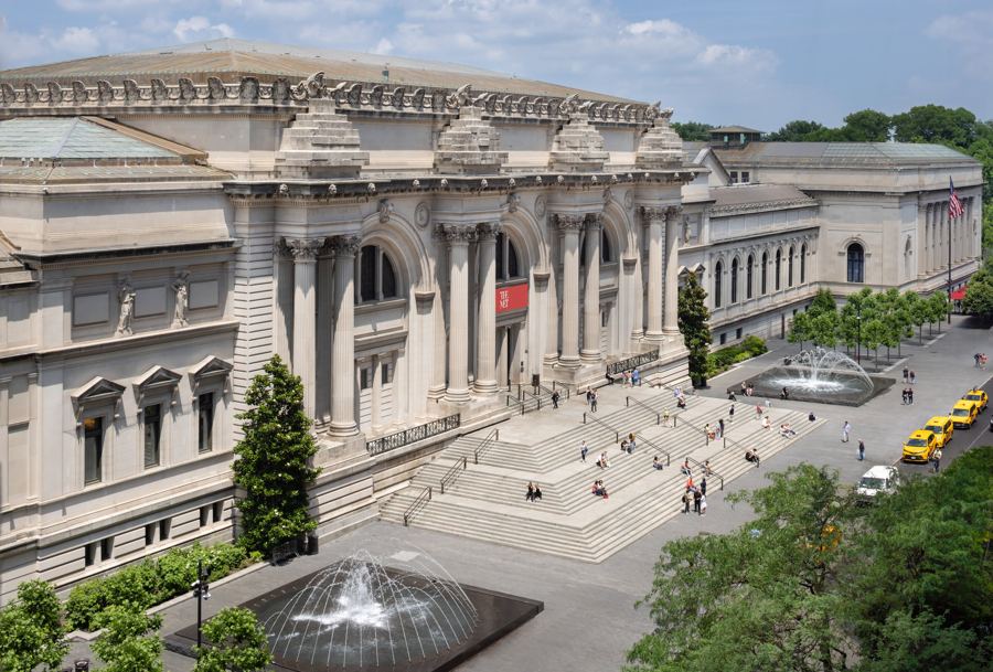 The Met's Beaux-Arts facade on Fifth Avenue from above, its broad steps and fountains busy with visitors