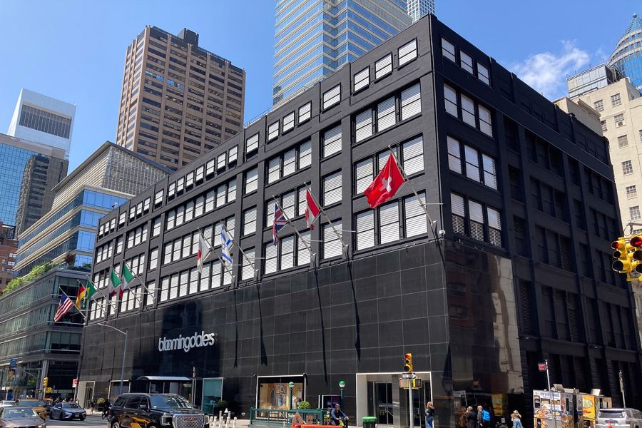 The black facade of Bloomingdale's flagship on Lexington Avenue, with a row of international flags above the entrance