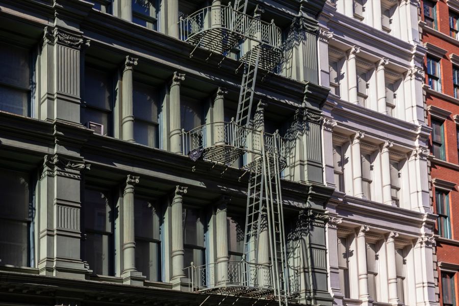Cast-iron building facades and fire escapes along a cobbled SoHo street in morning light