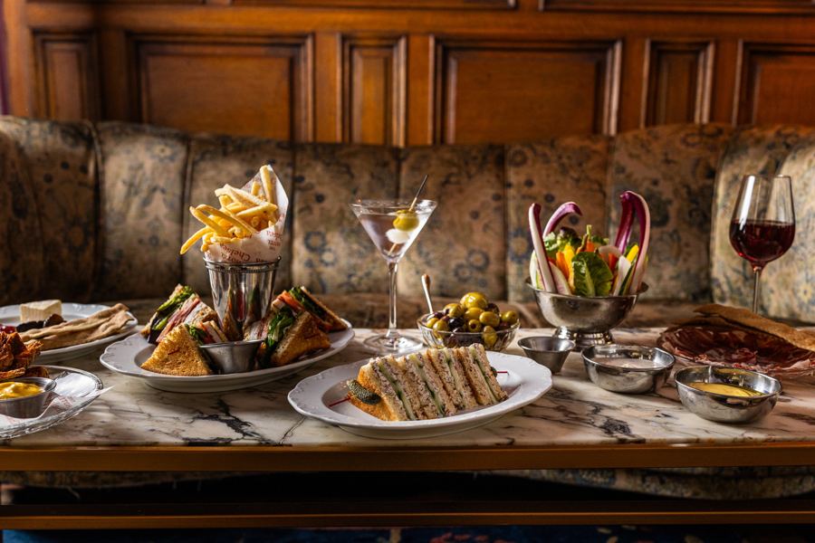 Club sandwiches, fries, crudités and martinis spread across a marble table in the Lobby Bar's banquette