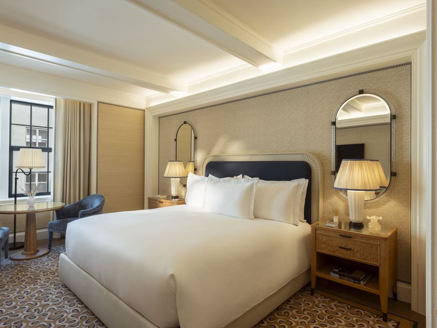 A Deluxe King room with a navy headboard, arched mirrors and a window onto the street