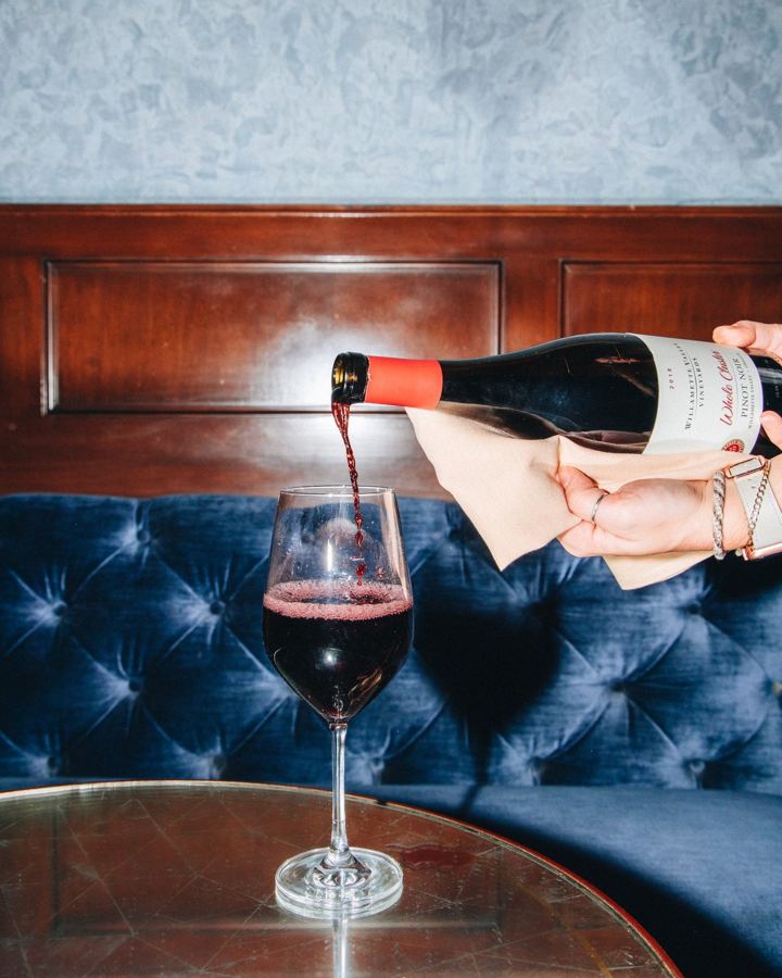 Red wine poured at a blue velvet banquette at Walker Hotel Greenwich Village
