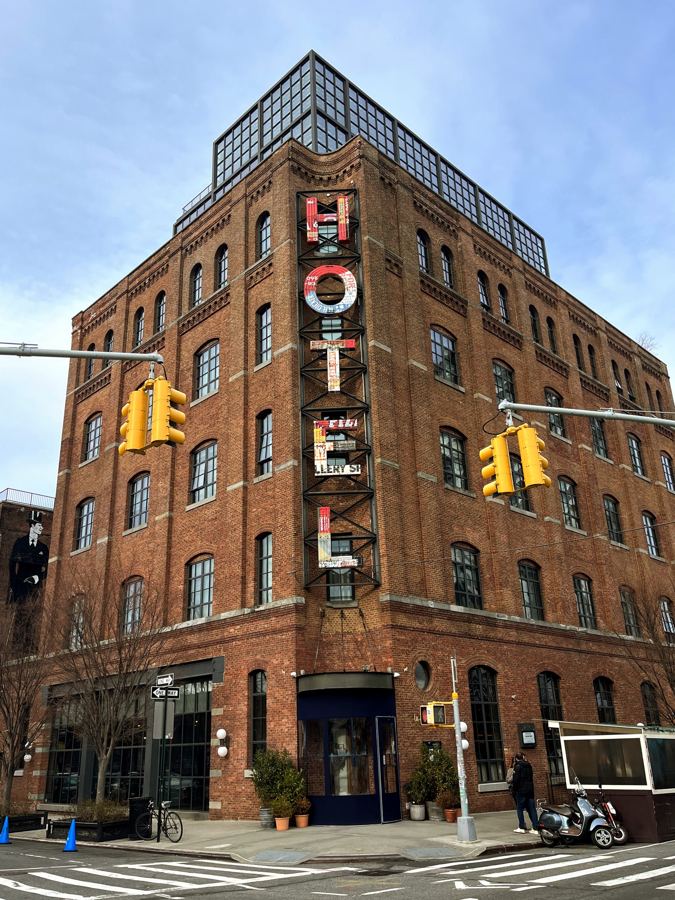 The brick facade and factory windows of the Wythe Hotel with Manhattan across the river