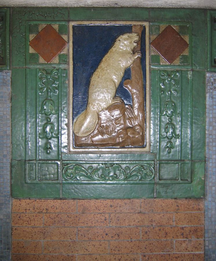 A glazed ceramic beaver in a green-and-blue tile frame on the wall of the Astor Place subway station