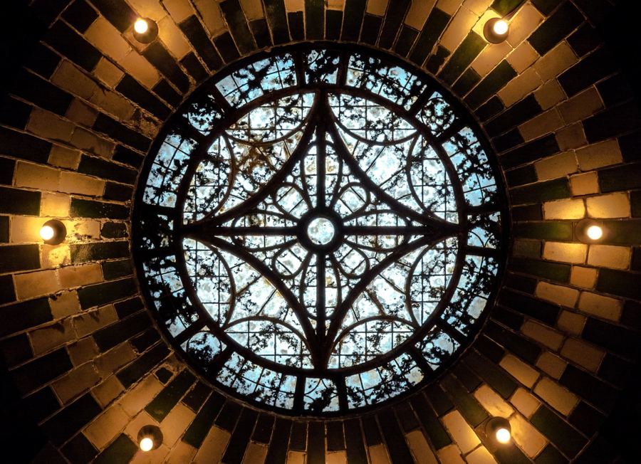 A leaded-glass skylight ringed by green and cream tile and bare bulbs in the vaulted ceiling of the abandoned City Hall subway station