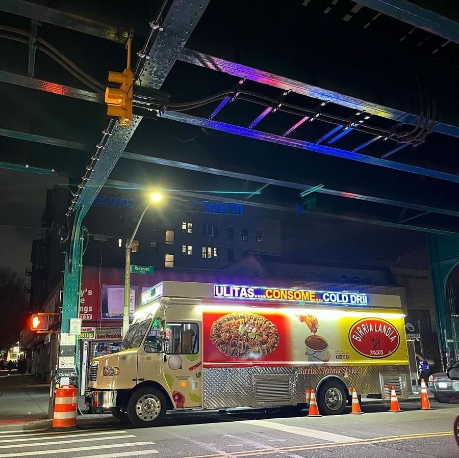 The Birria-Landia truck lit up at night on Roosevelt Avenue, "Birria Tijuana Style" on its side