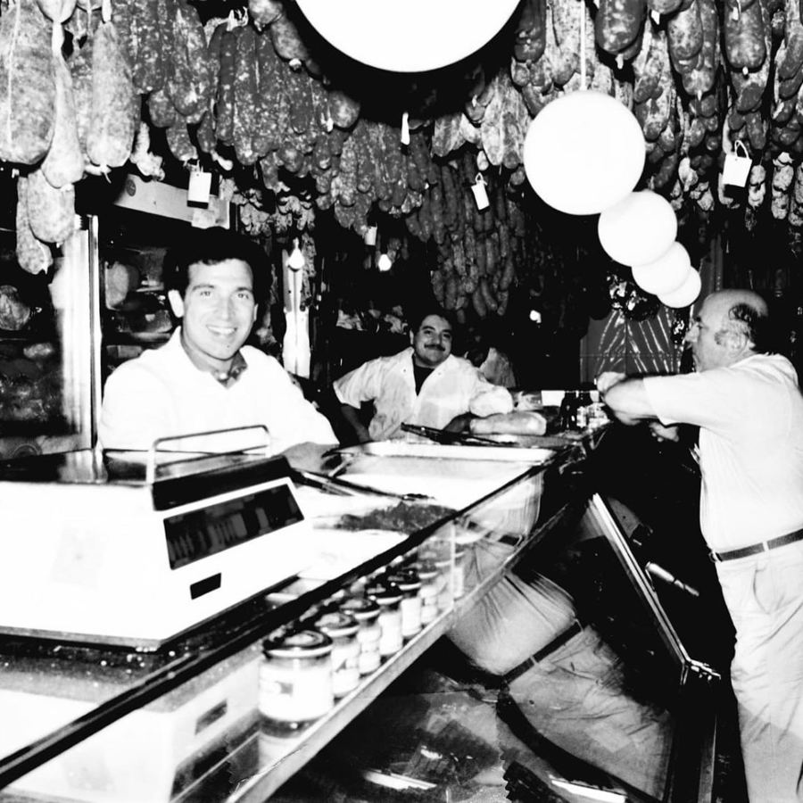 A vintage photo of the counter at Calabria Pork Store under the hanging sausages