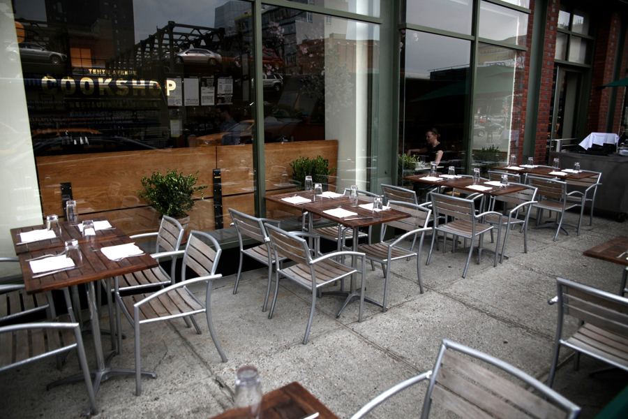 The sidewalk patio and tall glass windows of Cookshop on Tenth Avenue in Chelsea, with the Cookshop name lettered on the window