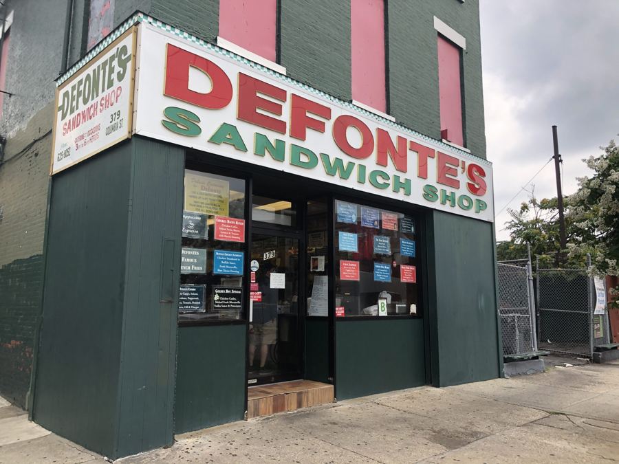 The green corner storefront of Defonte's Sandwich Shop in Red Hook under its big red-and-green painted sign.