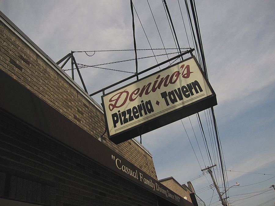 The hanging Denino's Pizzeria Tavern sign above the brick storefront on Port Richmond Avenue, Staten Island
