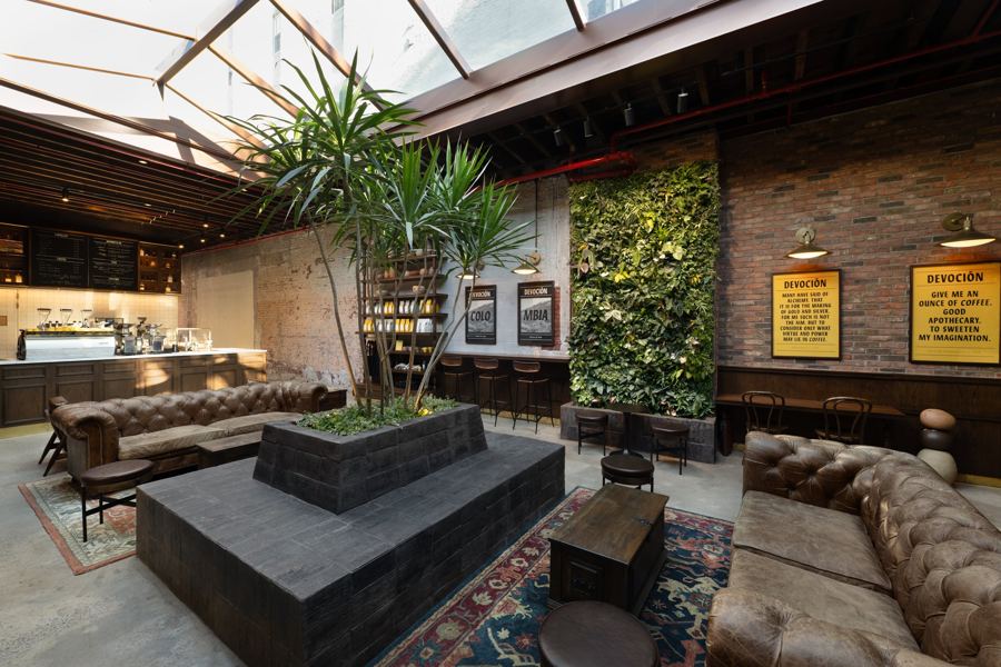 Leather sofas, palms and a living green wall under the skylight at Devoción on Grand Street