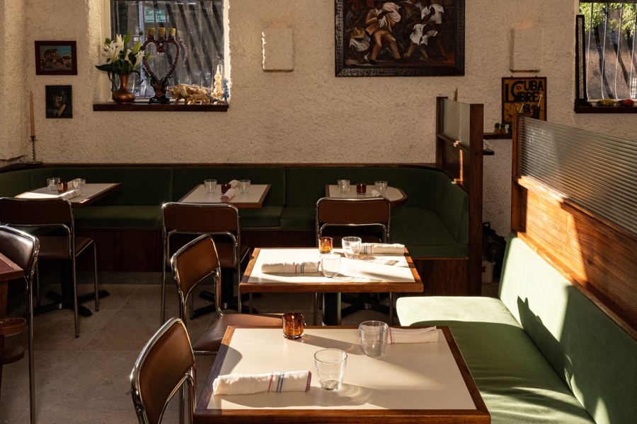 Late sun across the green banquettes and set tables at Dolores in Bed-Stuy