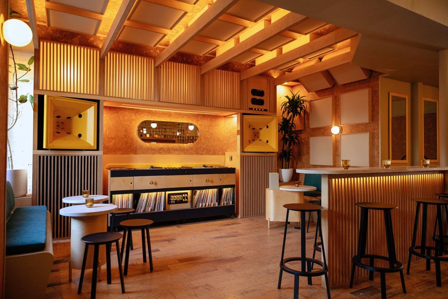 The wood-panelled listening room at Eavesdrop in Greenpoint, with the record shelves and DJ booth, bar stools and warm overhead light