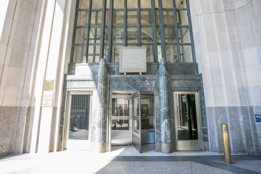 The soaring Art Deco entrance of Eleven Madison Park, with green marble columns, bronze doors and a stone plaque bearing the restaurant's name.