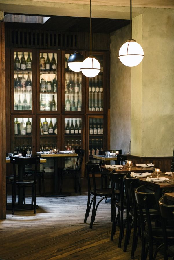 Estela's dining room above Houston Street — globe pendant lights, bentwood chairs and a tall wooden wine cabinet