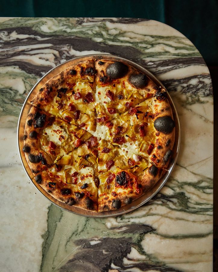 A golden pie with roasted toppings on swirled marble
