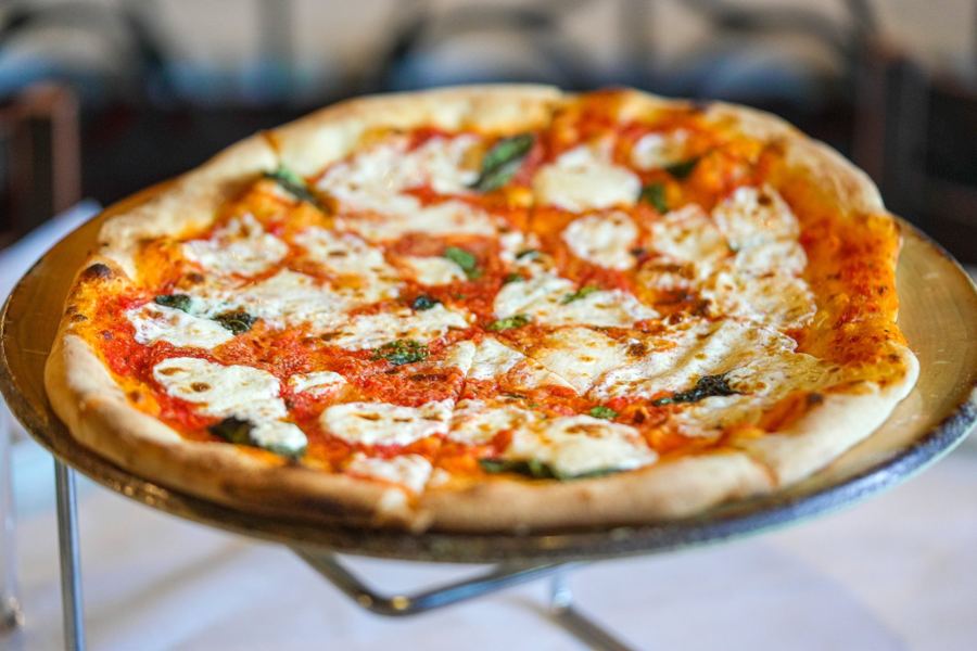 A margherita-style pizza on a stand at F & J Pine