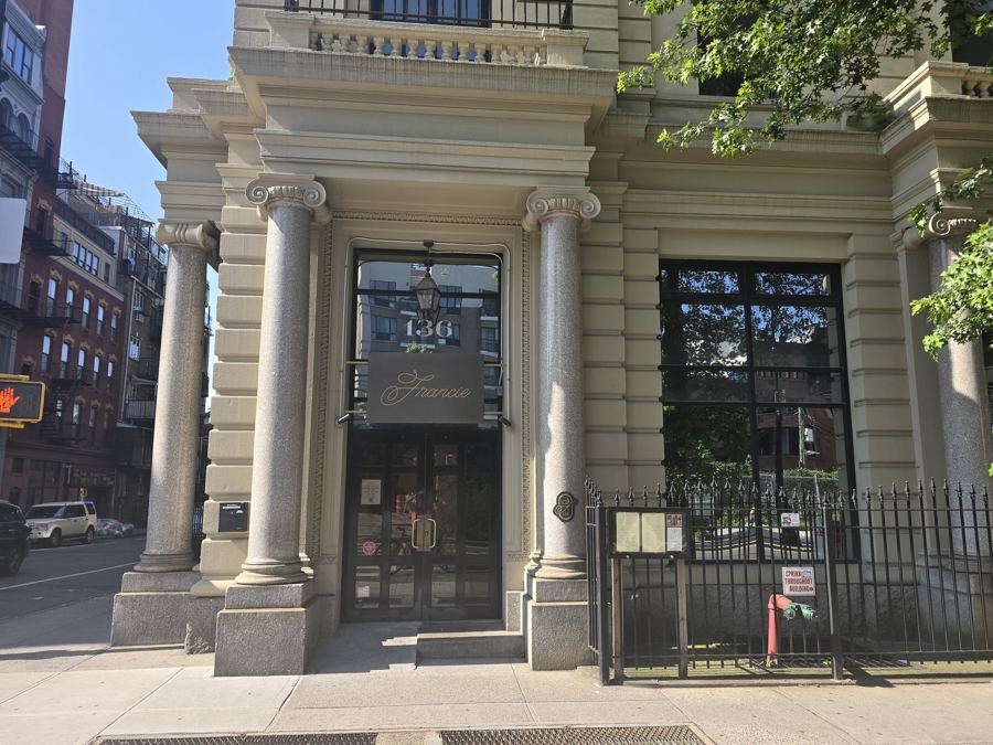 The columned entrance of Francie in a cream-colored former bank building on Broadway in Williamsburg, with a 'Francie' plaque over the glass doors