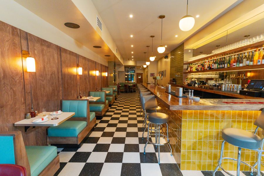 The long room at Frenzie: teal booths, a yellow-tiled bar and a black-and-white checkerboard floor