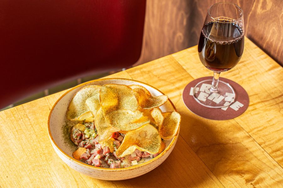 Beef tartare under crisp potato chips, with a glass of red