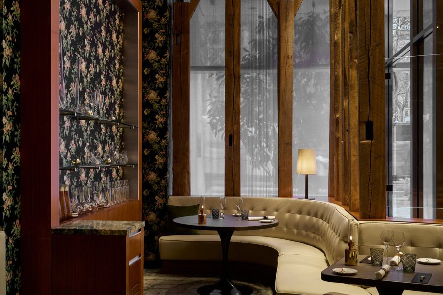 Curved cream banquettes and round tables beside tall windows in Gabriel Kreuther's dining room