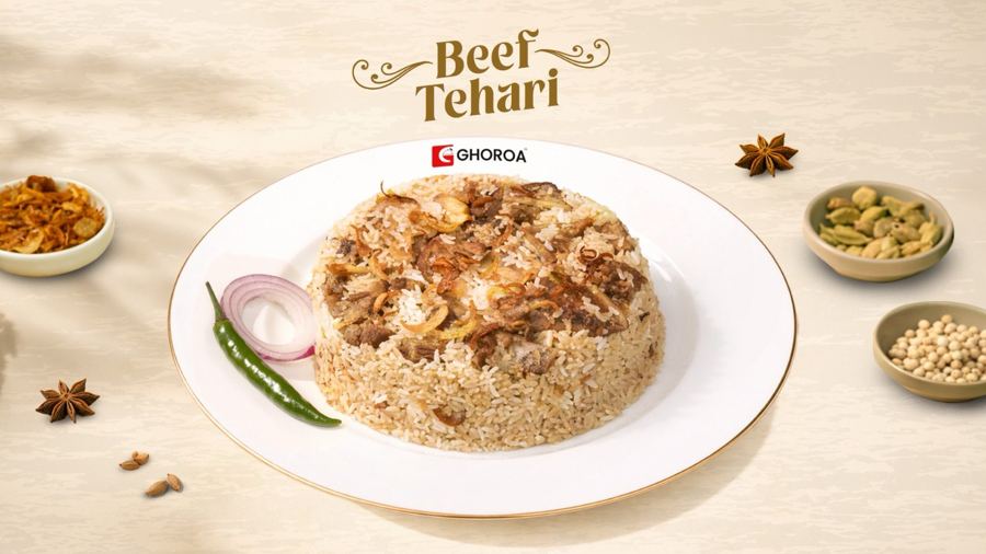 A plate of beef tehari with fried onions and a green chili, surrounded by small bowls of spices, from Ghoroa