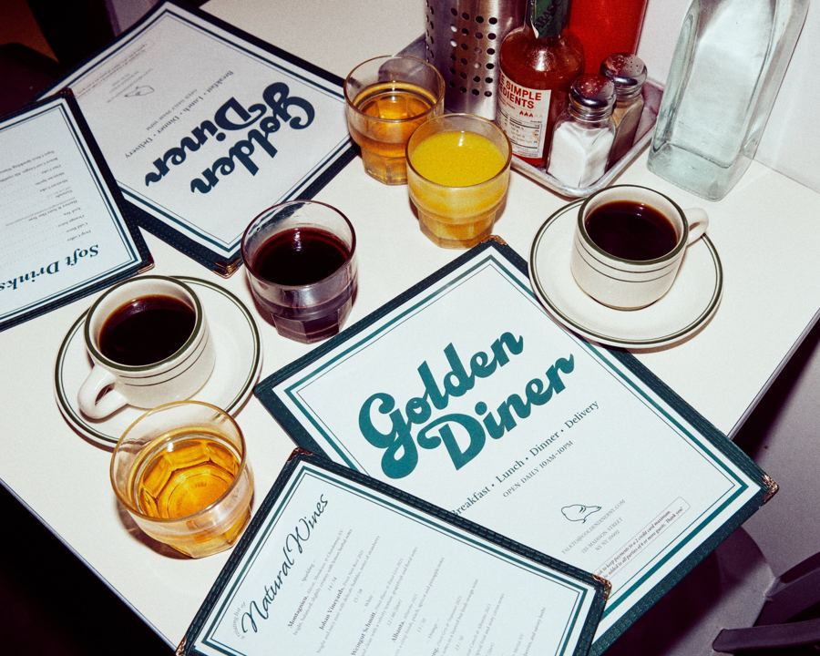 Golden Diner menus on a white table with coffee, orange juice and red wine