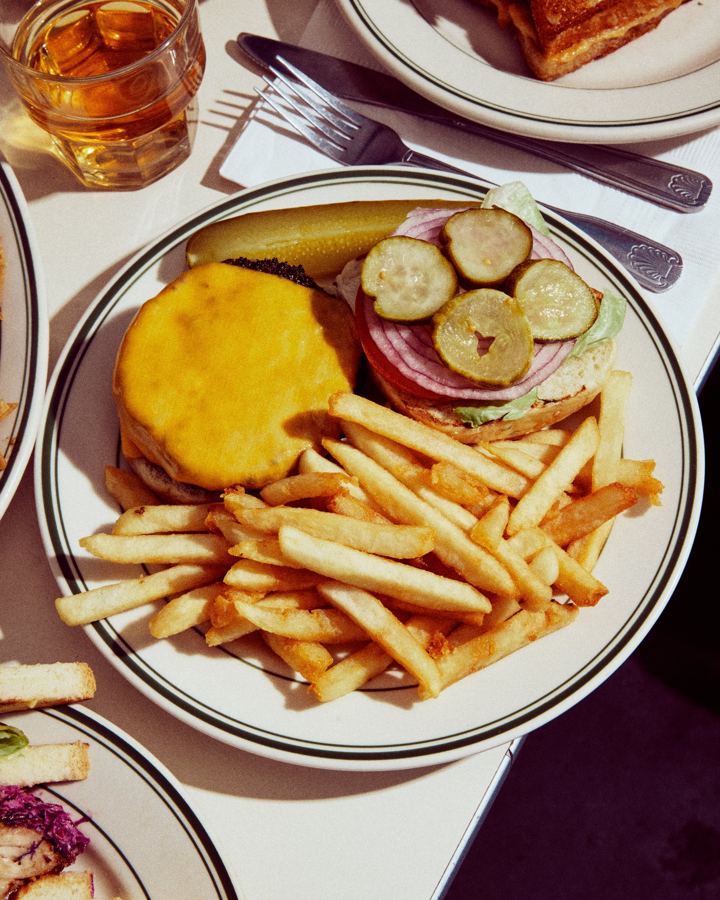 A cheeseburger with pickles and onion and a pile of fries at Golden Diner
