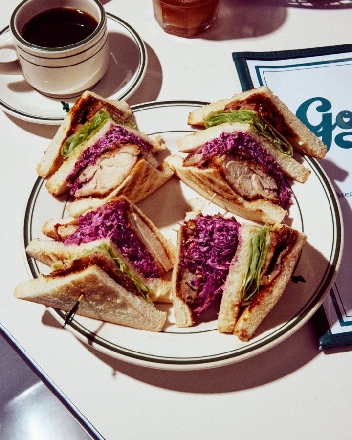 A Golden Diner club sandwich with red cabbage slaw, cut into quarters