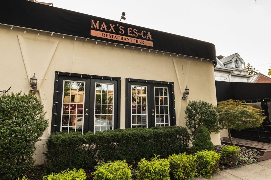 The cream-colored front of Max's Es-Ca on Richmond Road, with its awning sign and hedges