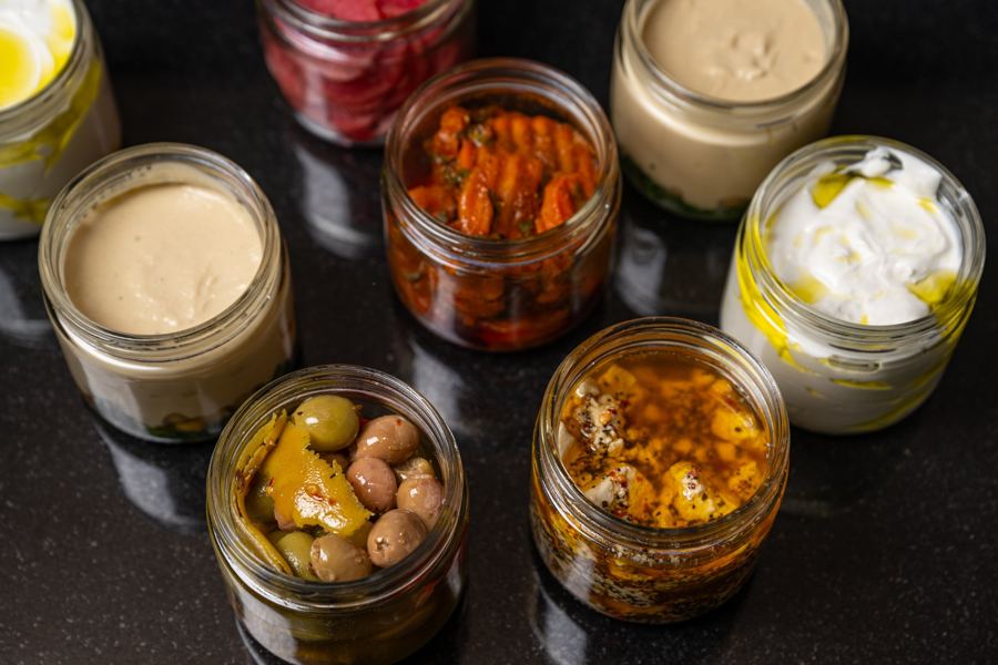 Jars of Messy's dips and pickles: tahini, labneh, olives and roasted peppers