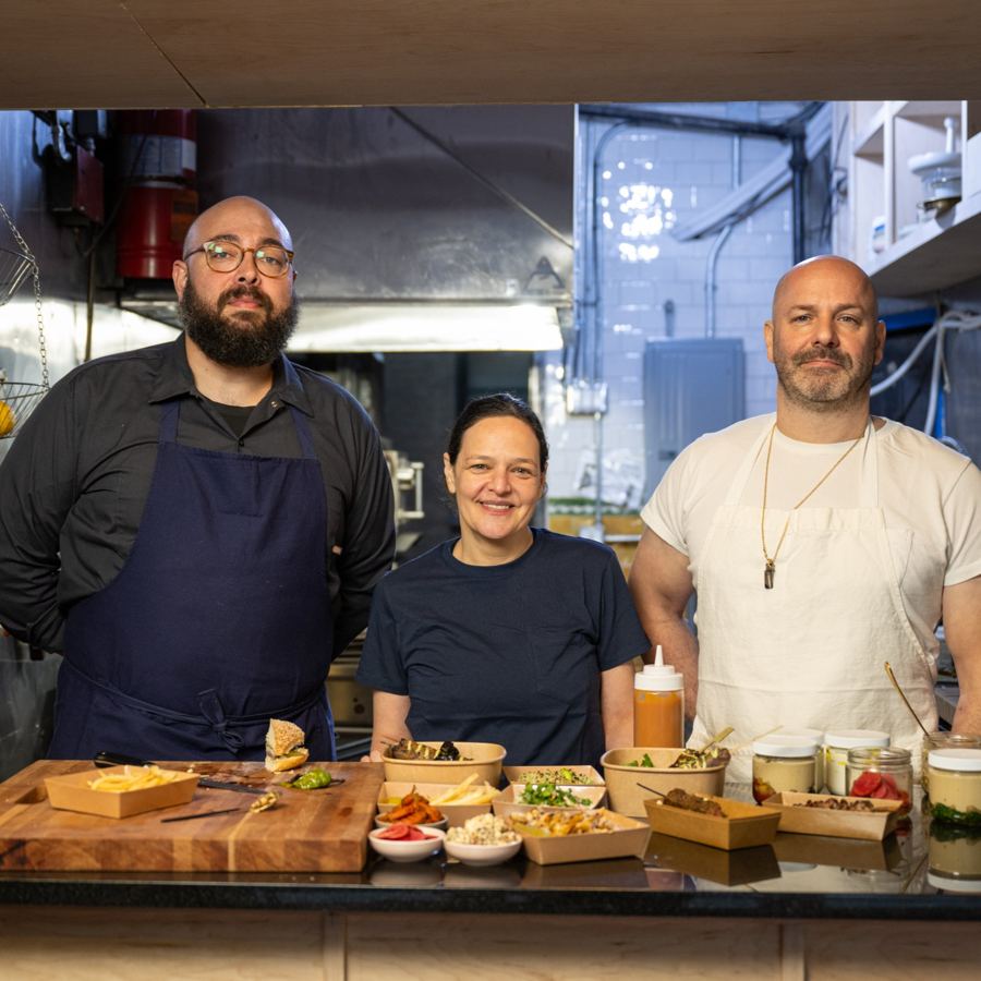The Messy team behind the counter with a spread of skewers, pitas and dips