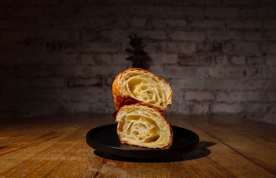 A butter croissant cut open on a black plate at Mottley Kitchen