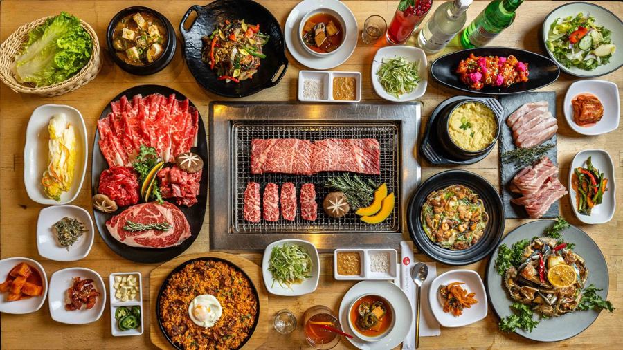 A Korean barbecue spread around the tabletop grill at New Wonjo in Koreatown, with marinated meats, banchan and stews