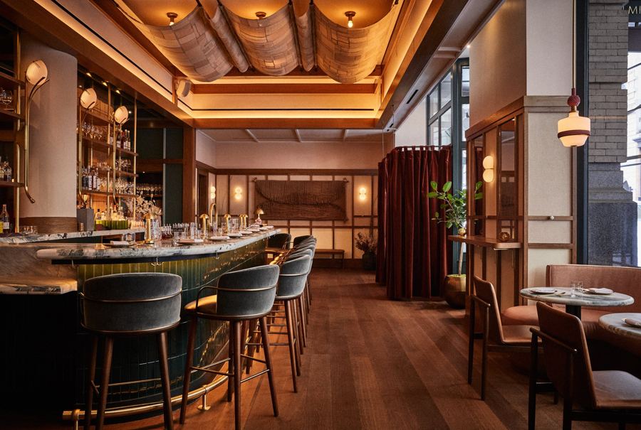 Oiji Mi's bar lounge: velvet stools along a curved marble bar under a draped, warmly lit ceiling, with a red-curtained alcove beyond