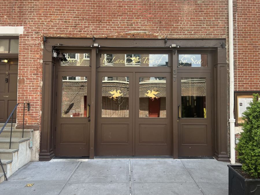 The brown carriage-house doors of One if by Land, Two if by Sea on Barrow Street, with gilded lettering and lantern motifs in the transom glass.