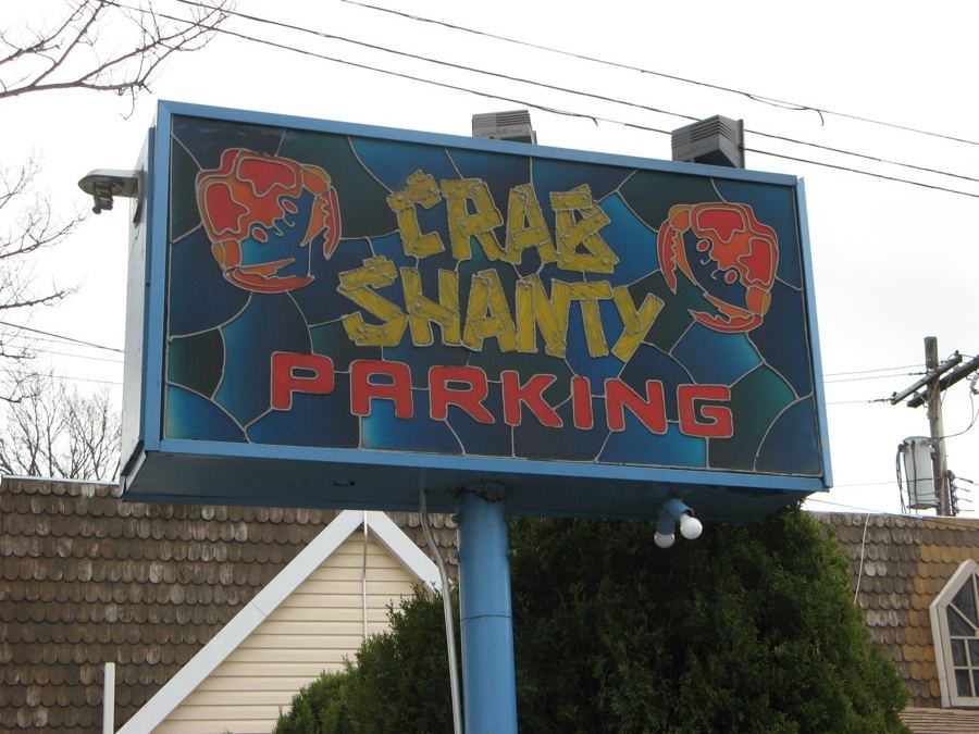 The stained-glass-style 'Crab Shanty Parking' sign with red crabs above the restaurant's lot on City Island Avenue