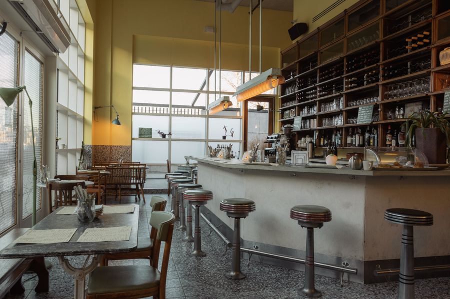Radio Star's long bar under tall windows, with wine shelves and red stools, near Transmitter Park