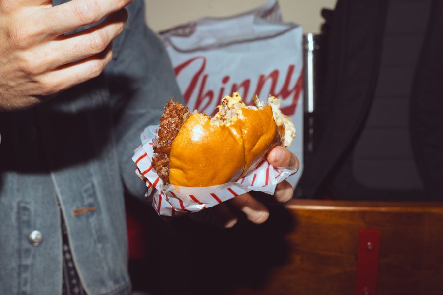 A Skinny Louie smash burger in its striped wrapper, cheese melting