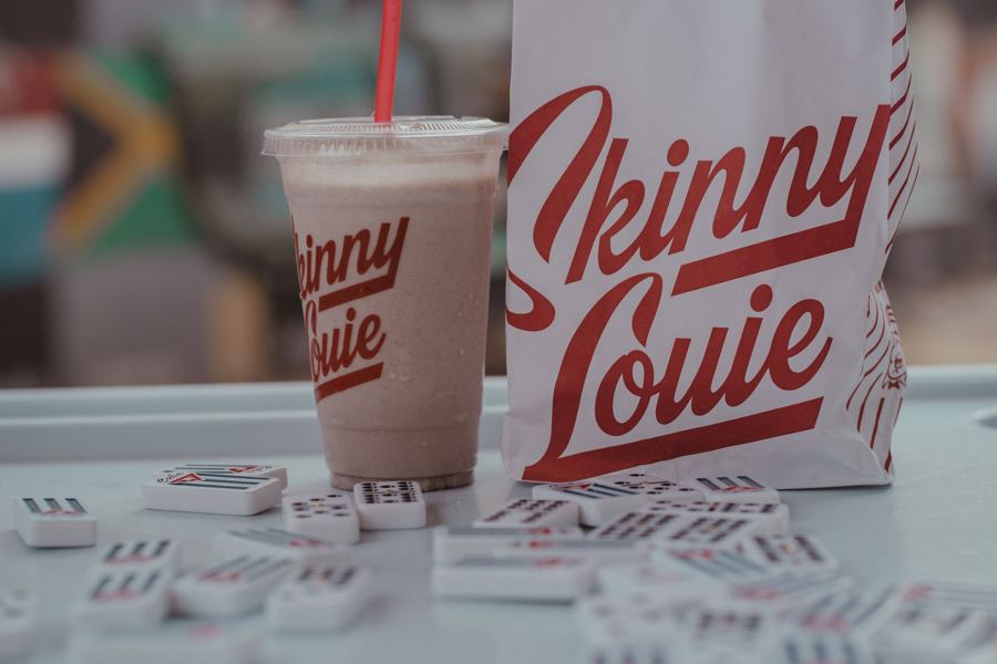 A Skinny Louie milkshake beside the striped takeout bag