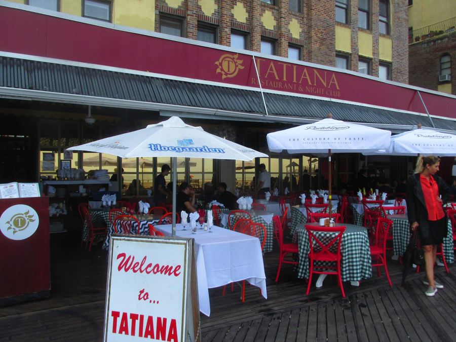 The maroon "Tatiana Restaurant & Night Club" awning over the boardwalk terrace in Brighton Beach, set with checked tablecloths and umbrellas